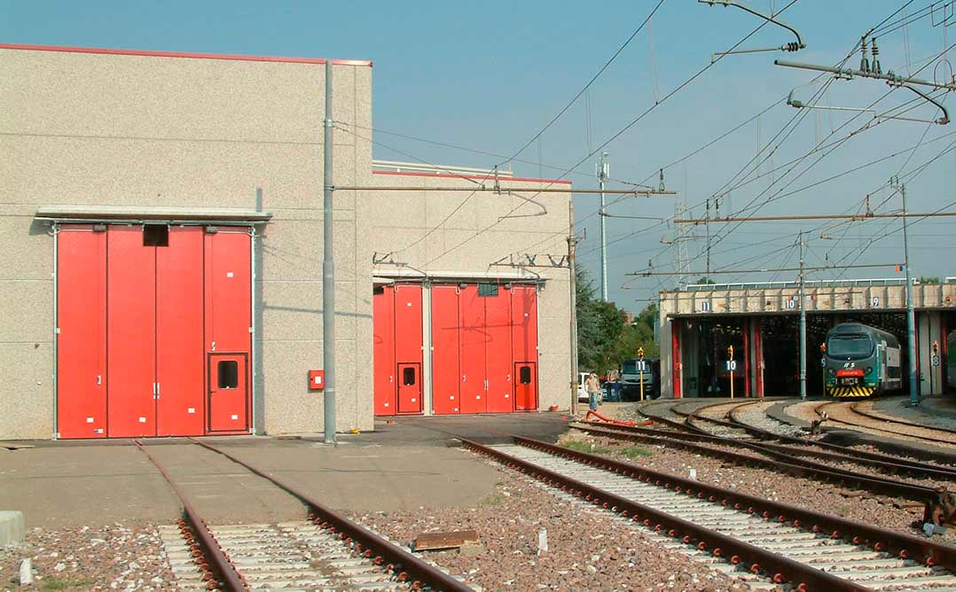 Portone industriale a libro per l'ingresso di mezzi di locomozione con alimentazione elettrica a filo superiore